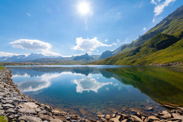 Sun and Clouds are reflecting in the clear water of a mountain lake. Melchsee-Frutt near Lucerne,...