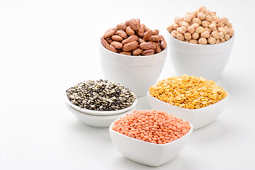 Uncooked lentils legumes and beans in bowl on white background assorted