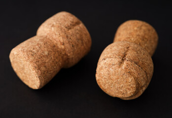 Two champagne corks lying on a black background.