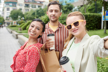 Smiling fashion blogger taking selfie with friends after shopping on Black Friday