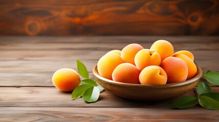 Fresh juicy apricots in a deep plate on a light wooden tabletop.