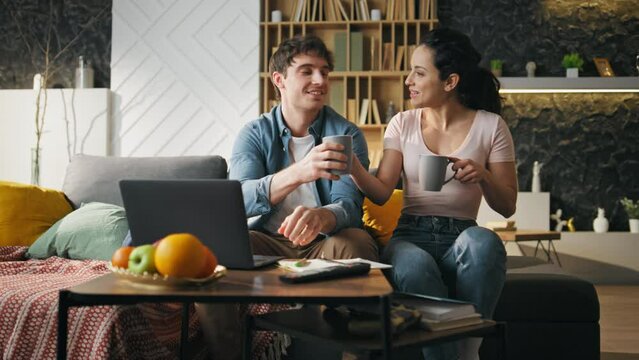 Relaxed family evening home in cozy living room. Woman bringing coffee to man