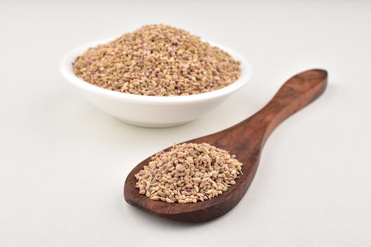 Closeup of carom seeds in spoon and bowl on white background