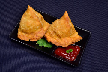 samosa with ketchup in plate on blue cloth 