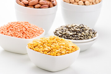 Variety of raw legumes and pulses in bowl on white background