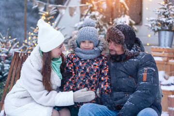 Happy family father and mother with son in winter nature. Portrait attractive caucasian parents hugging cute child in snowy forest. Family enjoying beautiful winter day outdoors