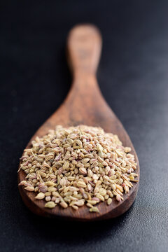 Ammi seeds in wooden spoon on dark background