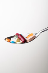Medicine pills in spoon on grey background