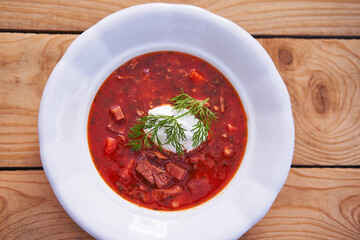 Traditional ukrainian borsch soup made from beef and pork meat, beet root, cabbage and vegetables, served with sour cream and dill in vintage white deep plate. Delicious eastern european tasty dish.