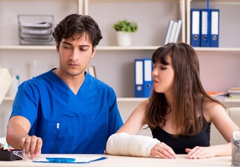 Obraz premium Young woman with bandaged arm visiting male doctor traumotologis