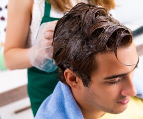 Naklejka premium Woman hairdresser applying dye to man hair