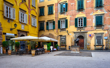 Old cozy street with tables of restaurant in Lucca, Italy - obrazy, fototapety, plakaty
