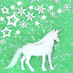 Christmas unicorn magical fantasy decoration with snowflake and star decorations on mottled green background. Festive happy holidays design for Yule, Noel, New Year.