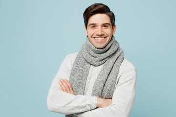 Young fun happy ill sick man in gray sweater scarf hold hands crossed folded isolated on plain blue...