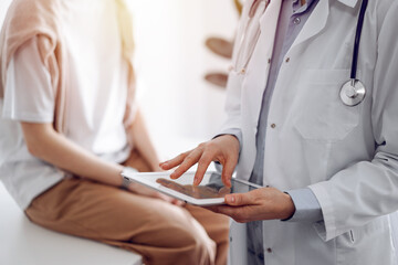 Doctor and patient in clinic. Friendly physician using tablet computer near a young woman. Medicine concept