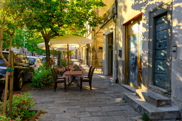 Old cozy street with tables of restaurant in Lucca, Italy. 