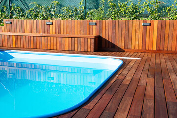 Hardwood pool deck in garden, deck planks fence and seating 