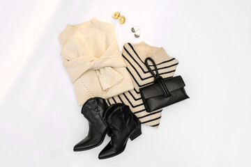 Warm sweaters with cowboy boots on white background. Women's stylish autumn or winter clothes. Cozy Winter look.  Flat lay, top view.
