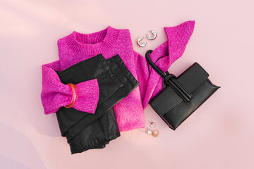 Pink jumper with leather pants and handbag on white background. Women's sweater stylish autumn or winter clothes. Cozy Winter look.  Flat lay, top view.
