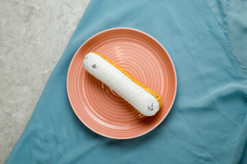 White Chocolate Eclair served in plate isolated on napkin top view of cafe baked food on background
