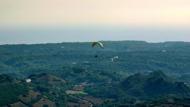 Bird's-eye view of Minorca's beauty with a drifting paraglider.