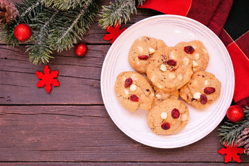 Christmas holiday white chocolate cranberry cookies. Above view table scene on a dark wood background.