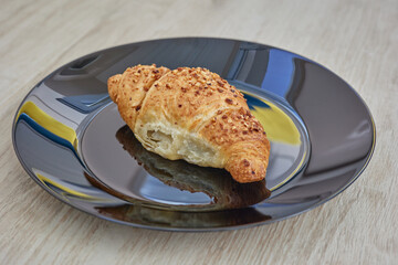 Croissant on a plate. Croissant with nougat cream sprinkled with almonds.