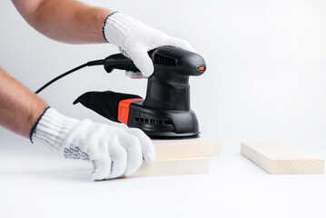 Eccentric grinding machine in hands. Power tool. On a white background. The master of wood blocks in gloves grinds