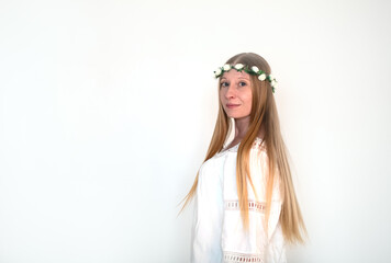 The innocent image of a young woman with long hair in a rose wreath and a white dress on a white background in the studio. Purity, harmony, identity and femininity.