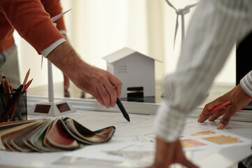 Team of construction engineers discussing building blueprint on desk in architectural bureau