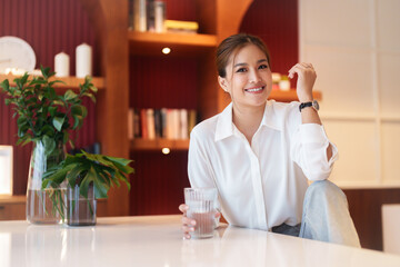 Woman sitting in living room to enjoying time with drinking fresh pure water and relaxation in home