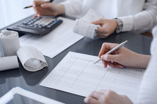 Two accountants use a calculator and tablet computer for counting taxes or revenue balance. Business, audit, and taxes concepts