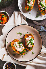 Baked sweet potato filled with ricotta, tomato and parsley on a plate top and vertical view