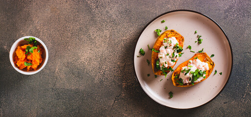 Baked sweet potato filled with ricotta, tomato and parsley on a plate top view web banner