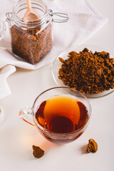 Healing tea from wild birch chaga mushroom in a cup on the table vertical view