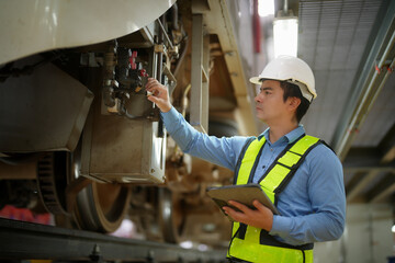 Engineers inspecting locomotive in railway engineering facility