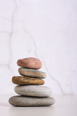 Pyramid of smooth sea stones on a table on the background of a plastered wall vertical view