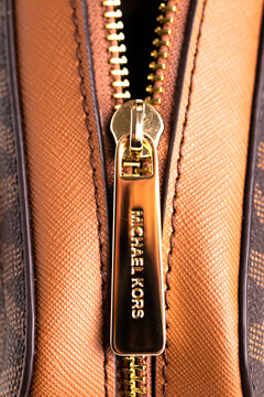 Metal gold-plated zipper on fashionable Michael Kors women's handbag. Accessory for woman's look. Close-up.