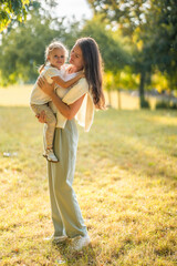 Fototapeta premium Young mother and cute little daughter playing together in autumn park in Prague, Europe
