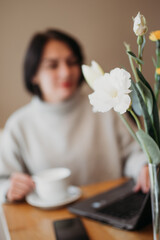 Image of happy woman using laptop while sitting at cafe