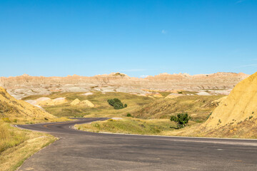 Fototapeta na wymiar A Winding Road Through The Yellow Mounds of Badlands National Park, South Dakota on a Clear Autumn Day 