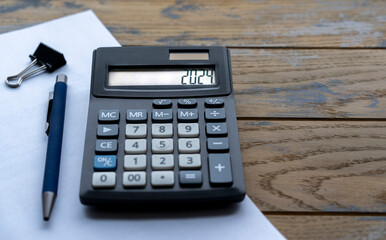 Calculator with the number 2024 on the display and stationery. Concept of finance, taxes, savings and economic crisis.