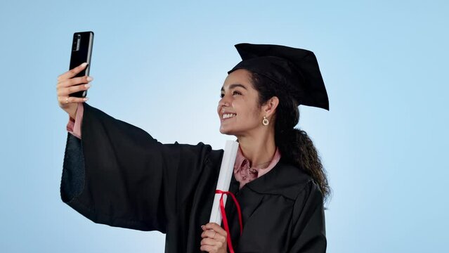 Selfie, celebration and woman with a degree, graduation and wink with certificate on a blue studio background. Person, model and student with a smartphone, social media and post with education or joy