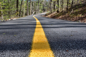 Cycling path low perspective. Yellow line leading to infinity. Bikeway with new asphalt and fresh paint job.