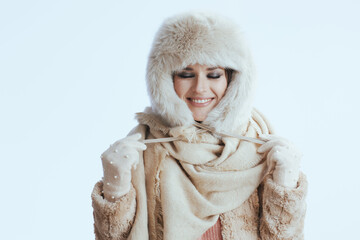 smiling stylish woman in winter coat and fur hat on white