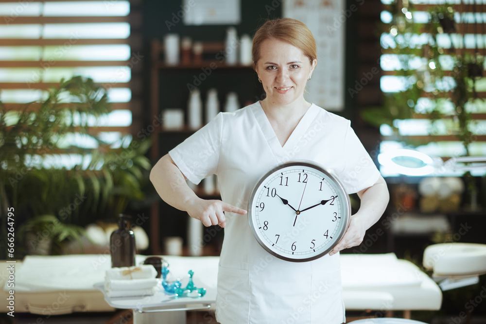 Poster smiling female medical massage therapist in massage cabinet