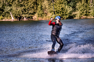 A man wakeboarding on a lake on summer day in a life  jacket. Soft focus. Action blur.