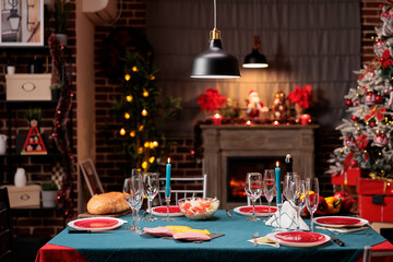 Christmas festive dinner on winter holiday, dining table with seasonal food and xmas decorations. Cozy decorated home with christmas tree and lights for traditional family party.