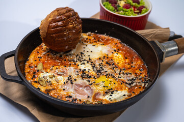 Homemade scrambled eggs with sausages in a pan on a light background. Classic breakfast. View from above. place for writing