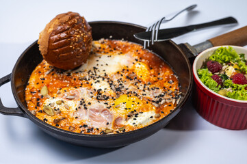 Homemade scrambled eggs with sausages in a pan on a light background. Classic breakfast. View from above. place for writing